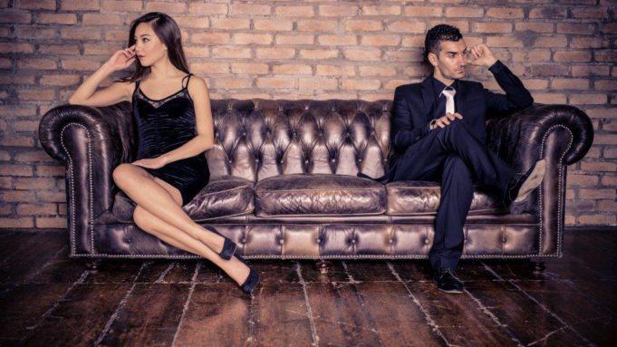 arguing couple sitting on opposite ends of sofa