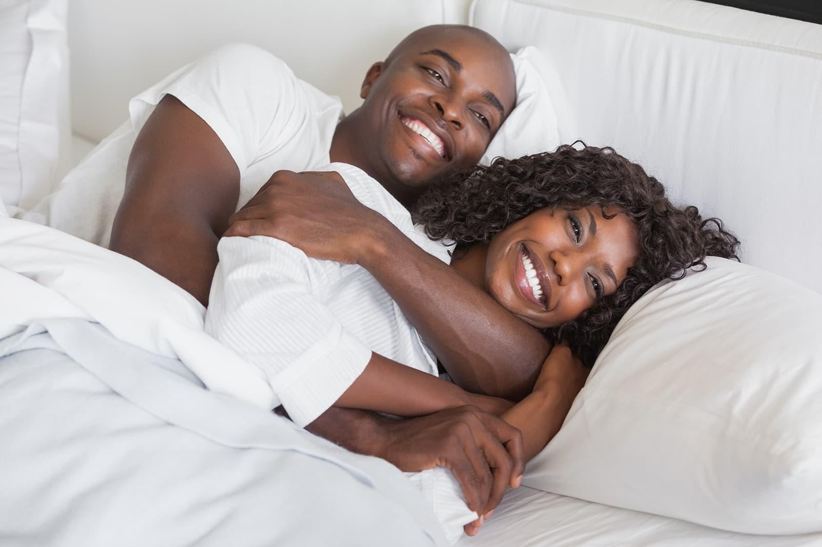 black couple hugging and laughing in bed